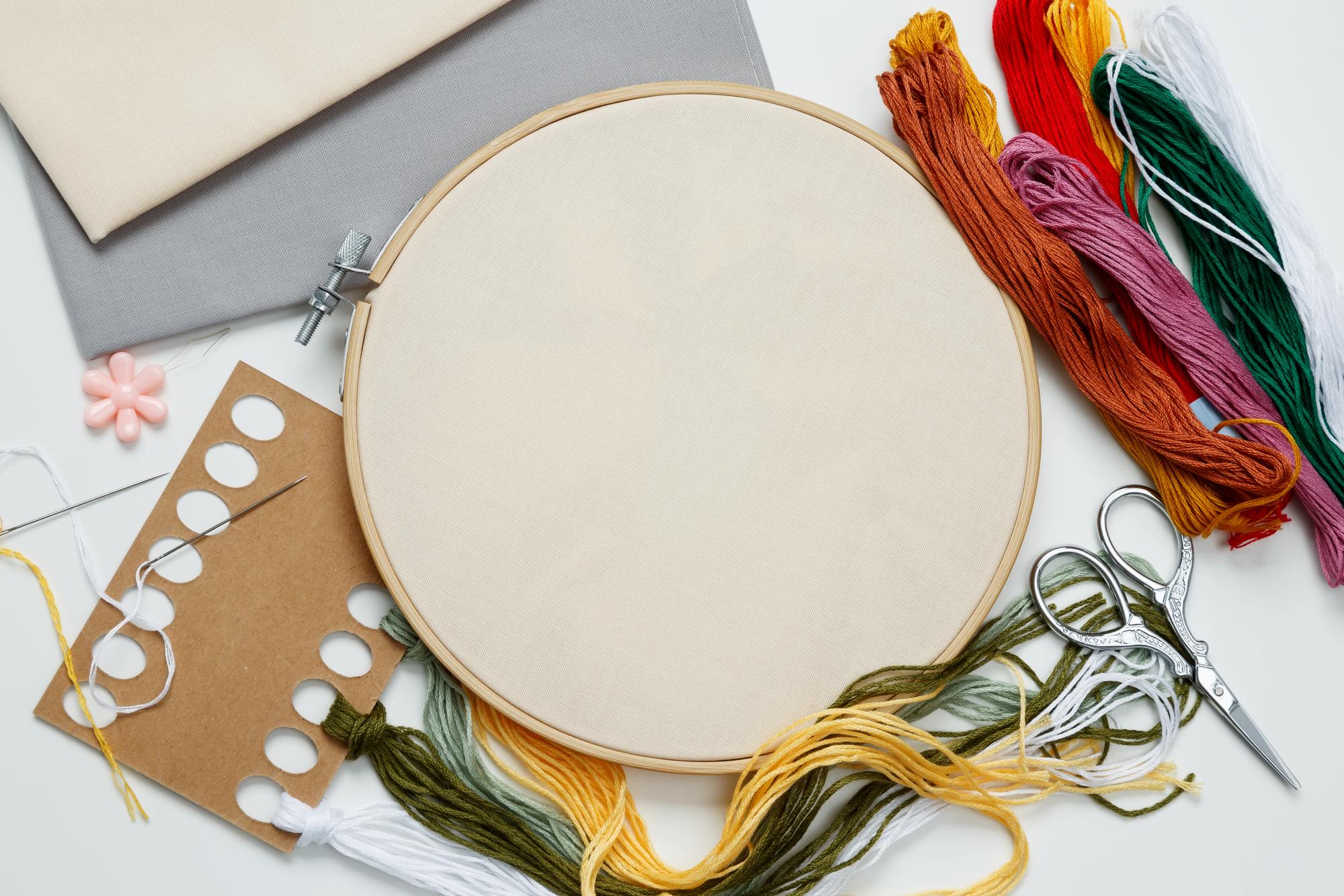 studio workspace with embroidery hoops and threads